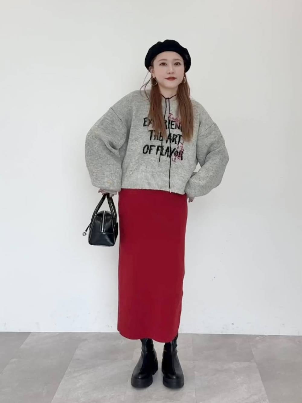 レッド系のスカート、ブラック系のブーツ、ブラック系のボストンバッグを着用したレディースの秋コーディネートの4枚目の写真