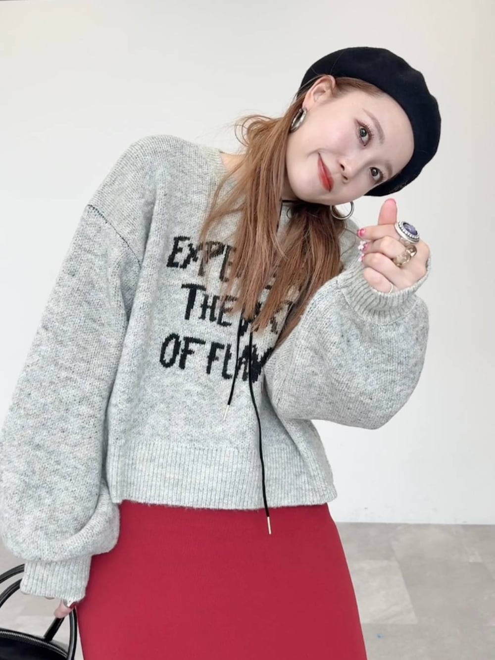 レッド系のスカート、ブラック系のブーツ、ブラック系のボストンバッグを着用したレディースの秋コーディネートの5枚目の写真