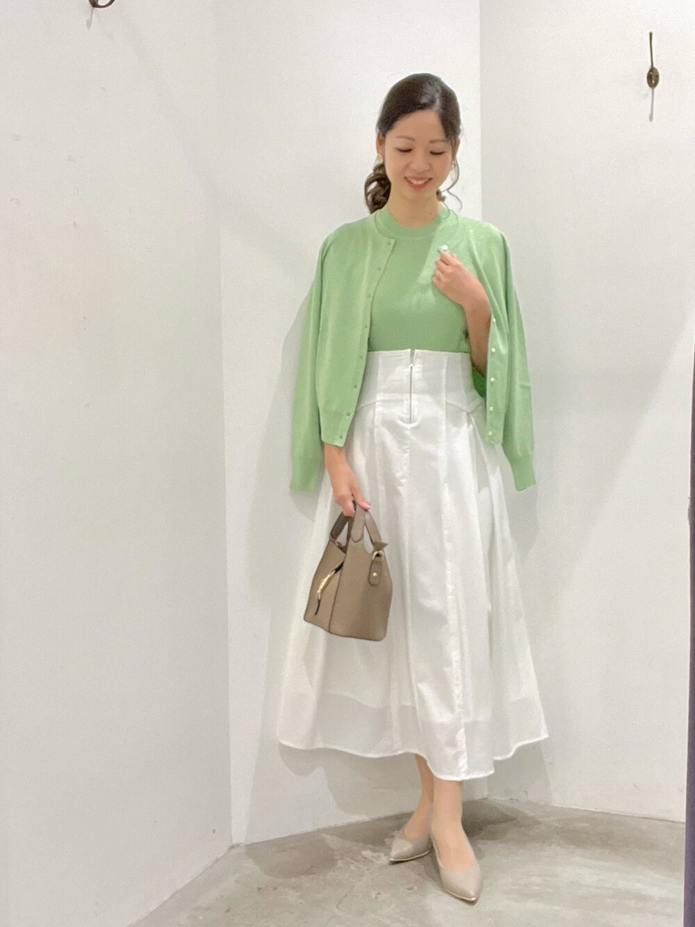 グリーン系のカーディガン/ボレロ、グリーン系のニット/セーター、ホワイト系のスカートを着用したレディースの春コーディネートの2枚目の写真