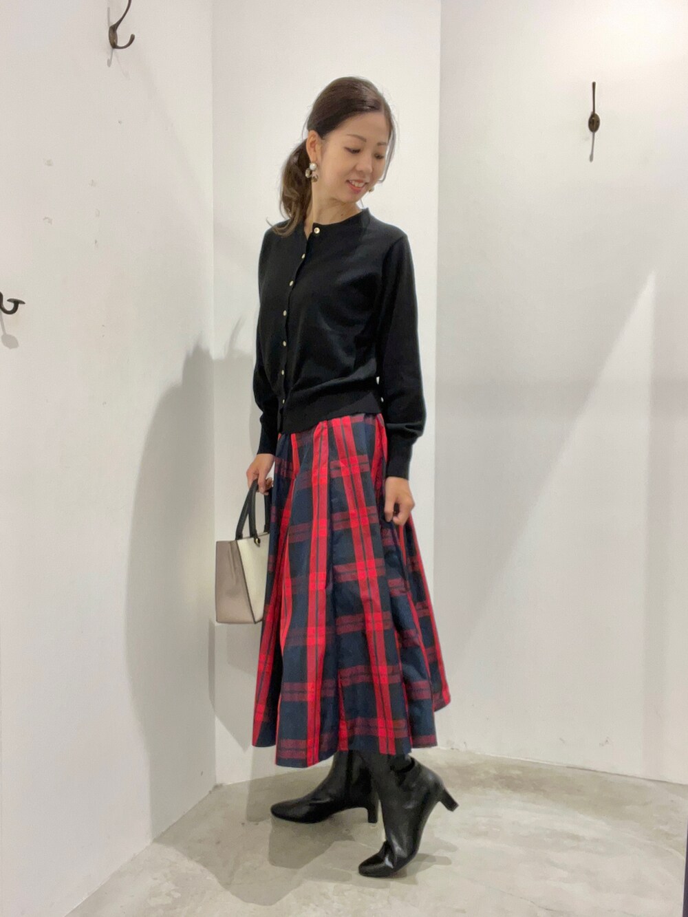 レッド系のスカート、ブラック系のカーディガン/ボレロ、ブラウン系のシューズを着用したレディースの秋コーディネートの2枚目の写真