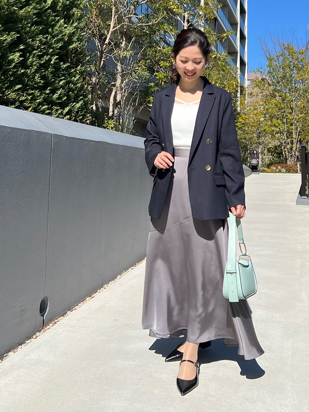 ブルー系のテーラードジャケット、ホワイト系のニット/セーター、グレー系のスカートを着用したレディースの春コーディネートの2枚目の写真