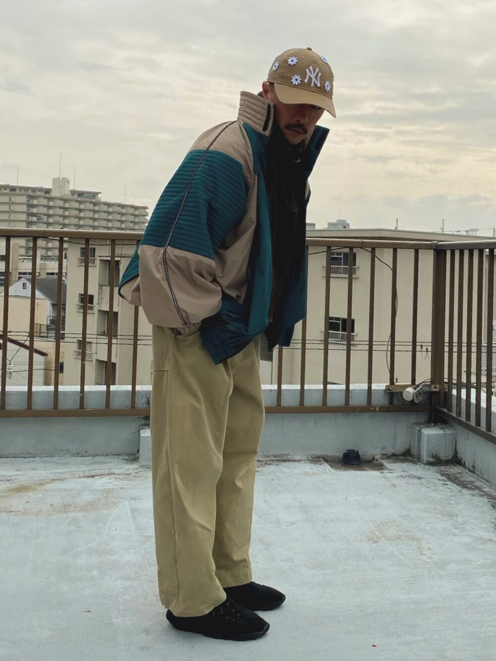 ベージュ系のブルゾン、グリーン系のその他パンツ、ブラック系のスニーカーを着用したメンズの冬コーディネートの2枚目の写真