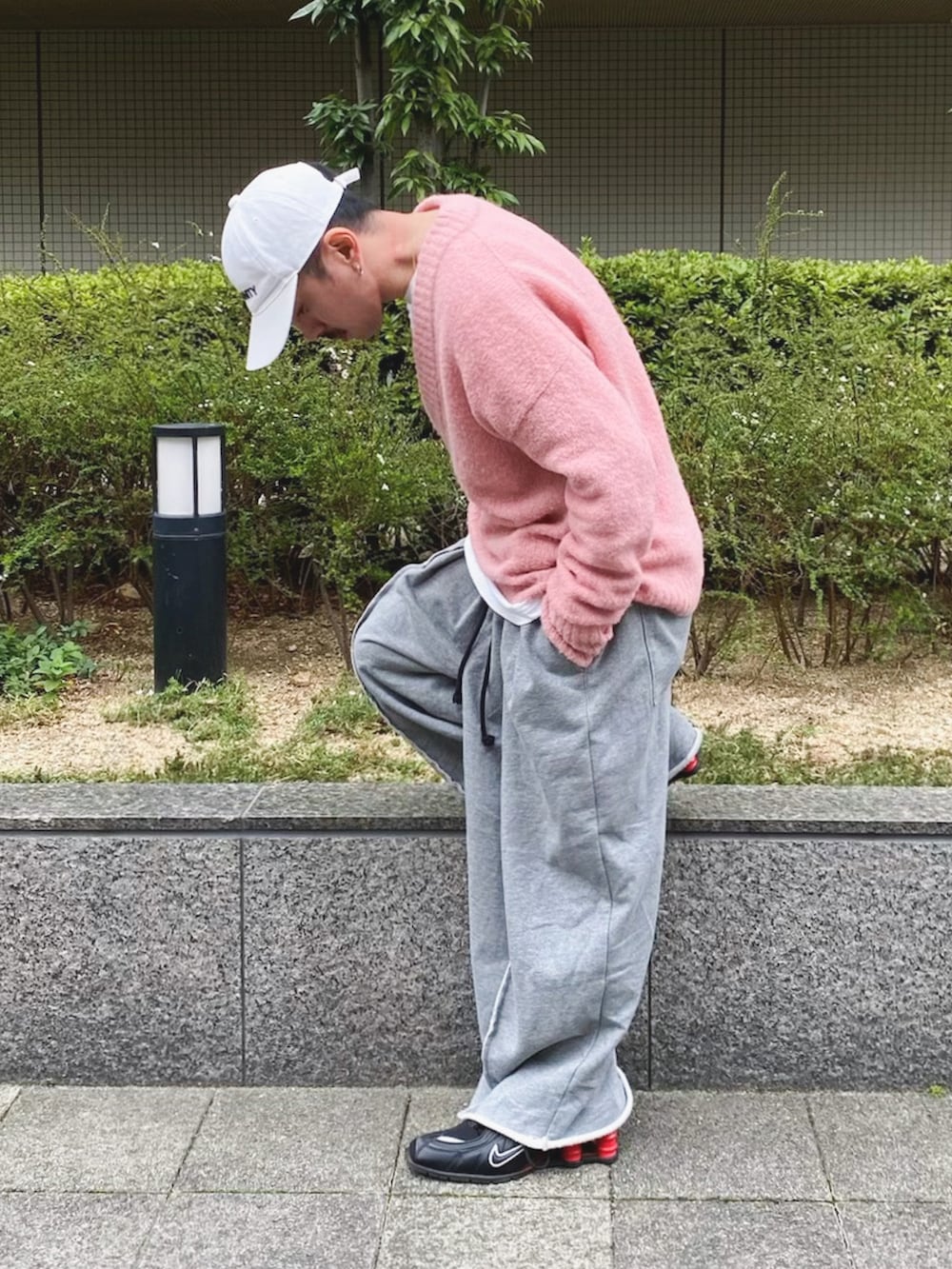 ピンク系のニット/セーター、グレー系のスウェットパンツ、ブラック系のスニーカーを着用したメンズの春コーディネートの2枚目の写真