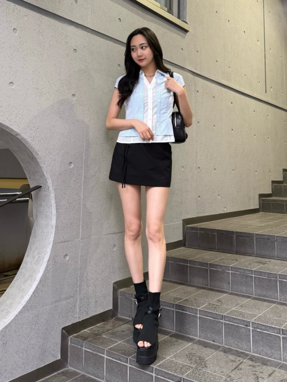 ブルー系のシャツ/ブラウス、ブラック系のショルダーバッグ、ブラック系のスカートを着用したレディースの夏コーディネートの2枚目の写真