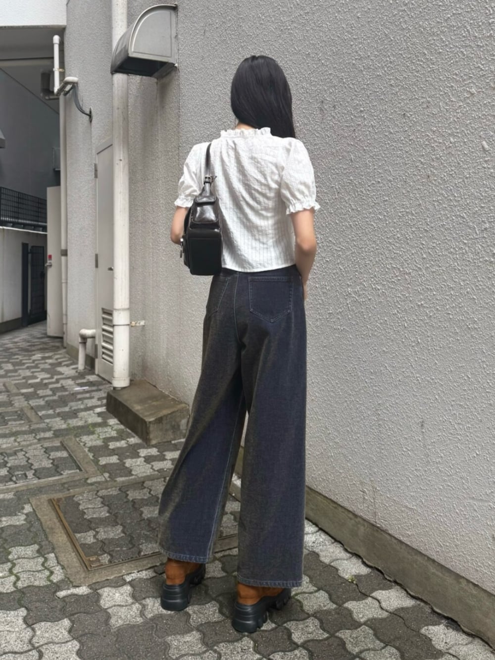 グリーン系のデニムパンツ、ブラウン系のブーツ、ブラック系のハンドバッグを着用したレディースの秋コーディネートの5枚目の写真