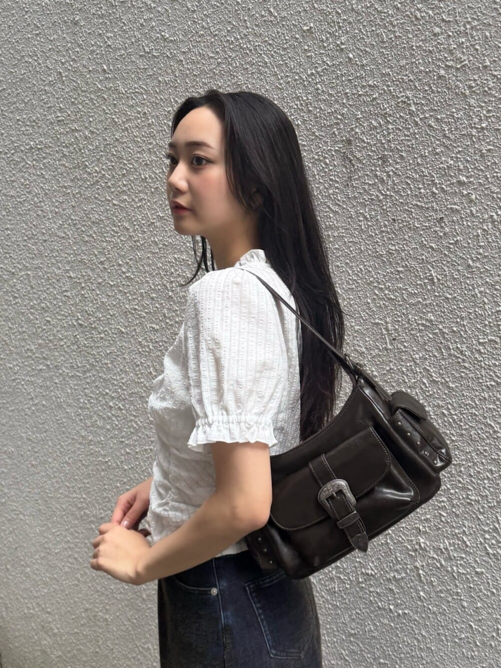グリーン系のデニムパンツ、ブラウン系のブーツ、ブラック系のハンドバッグを着用したレディースの秋コーディネートの8枚目の写真