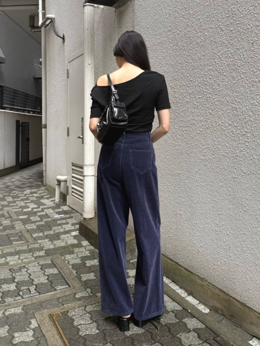 ブラック系のハンドバッグ、パープル系のデニムパンツ、ブラック系のパンプスを着用したレディースの夏コーディネートの3枚目の写真