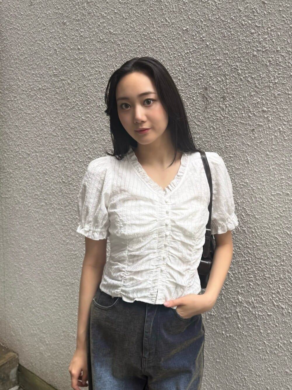 グリーン系のデニムパンツ、ブラウン系のブーツ、ブラック系のハンドバッグを着用したレディースの秋コーディネートの6枚目の写真