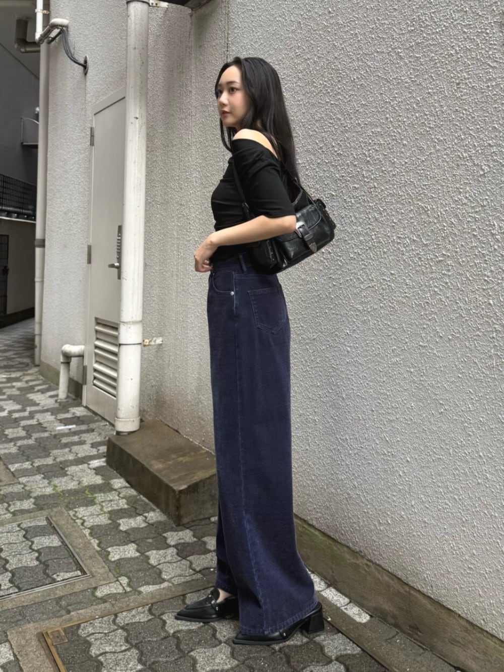 ブラック系のハンドバッグ、パープル系のデニムパンツ、ブラック系のパンプスを着用したレディースの夏コーディネートの2枚目の写真