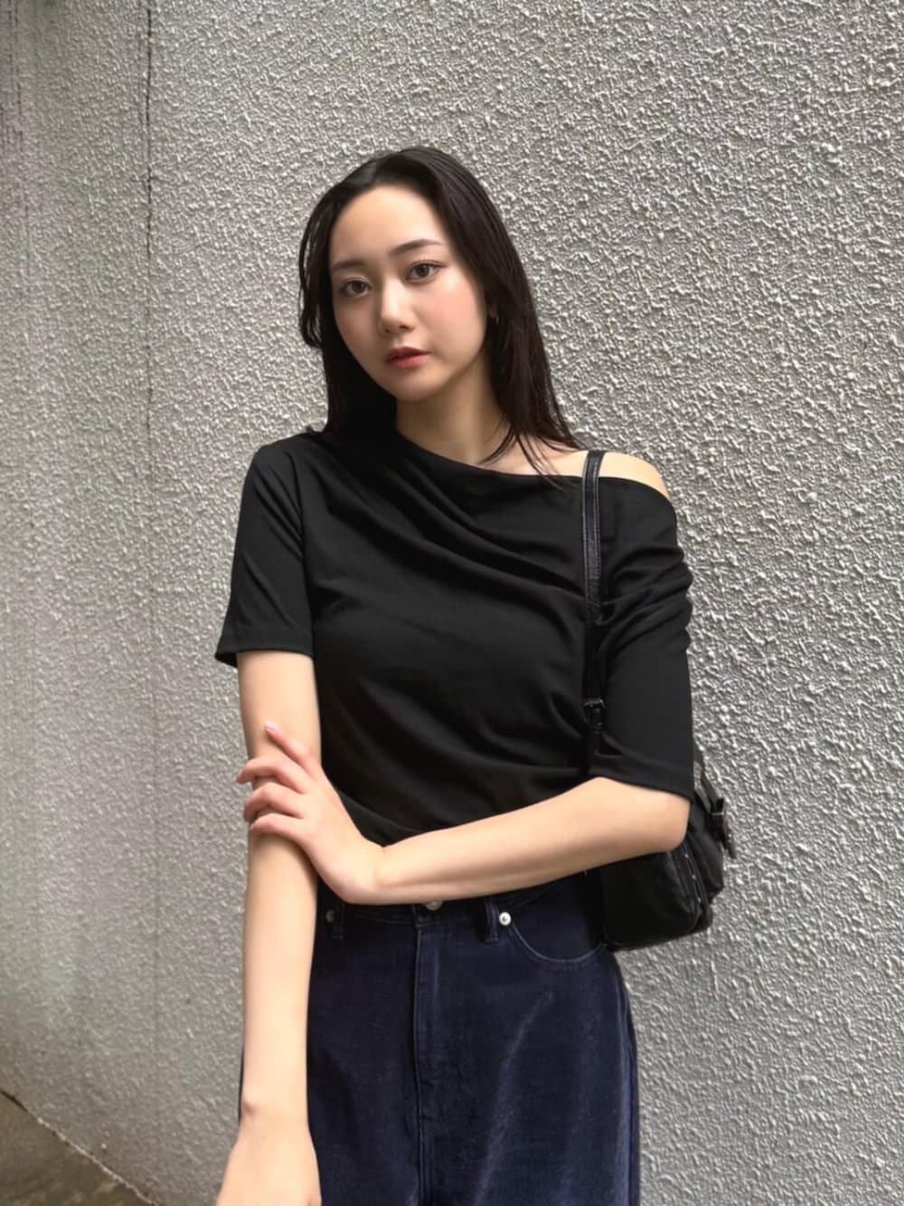 ブラック系のハンドバッグ、パープル系のデニムパンツ、ブラック系のパンプスを着用したレディースの夏コーディネートの5枚目の写真