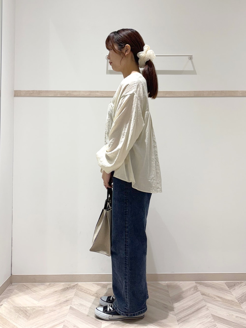 ホワイト系のカーディガン/ボレロ、ゴールド系のタンクトップ、ブルー系のデニムパンツを着用したレディースの秋コーディネートの2枚目の写真