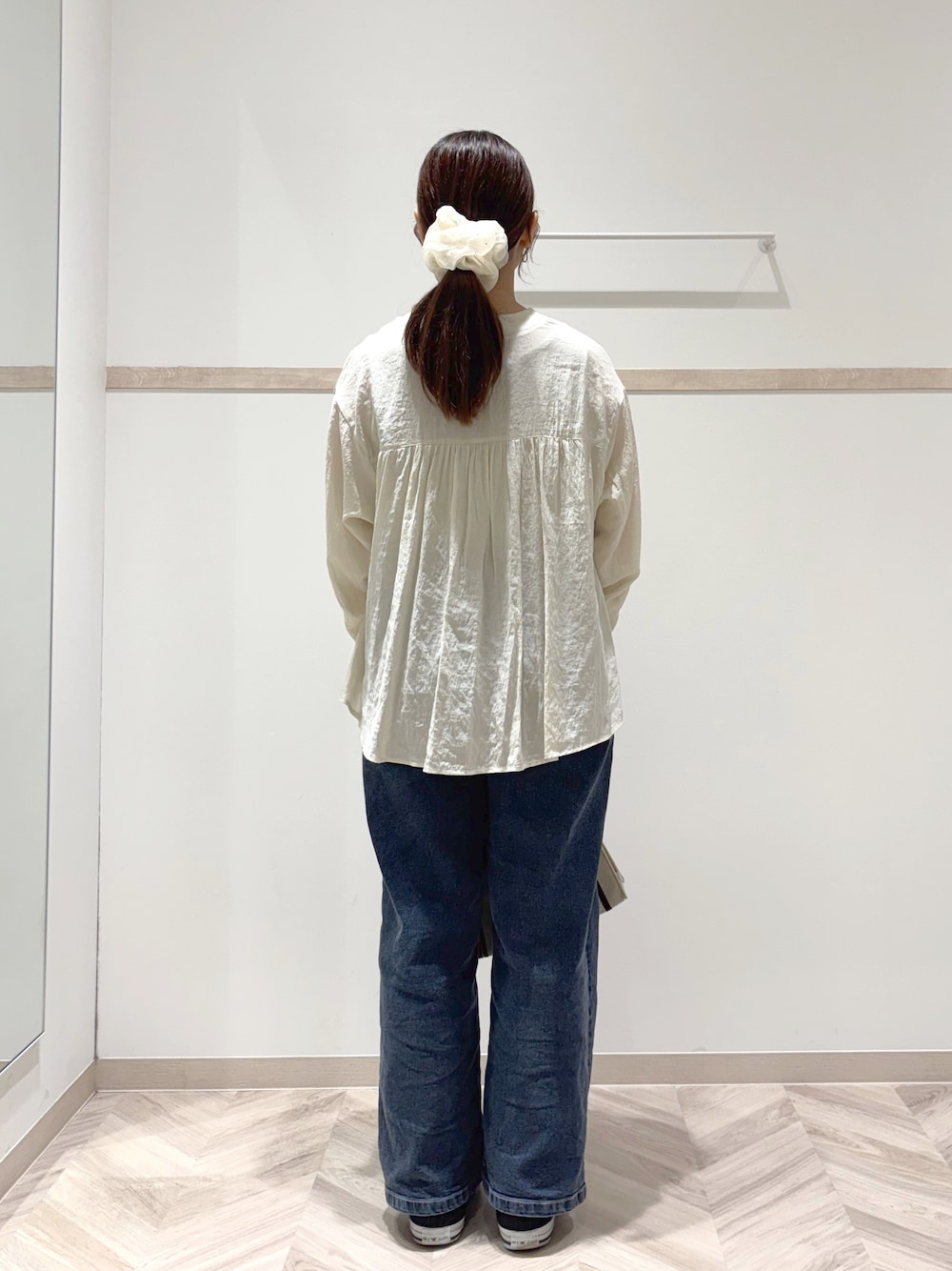 ホワイト系のカーディガン/ボレロ、ゴールド系のタンクトップ、ブルー系のデニムパンツを着用したレディースの秋コーディネートの3枚目の写真