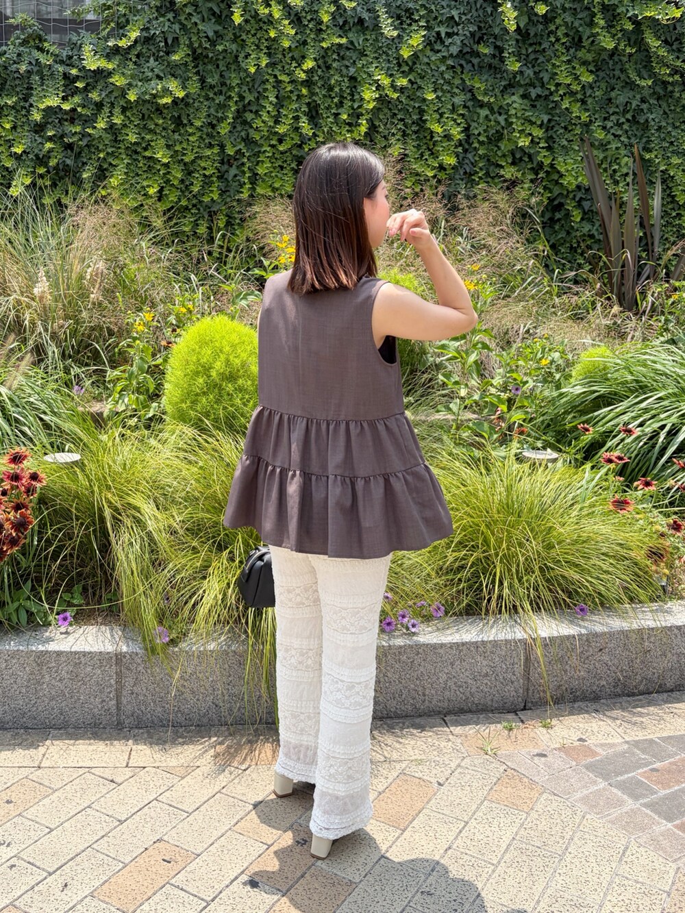 ブラウン系のベスト、ホワイト系のその他パンツ、ブラック系のボストンバッグを着用したレディースの夏コーディネートの3枚目の写真