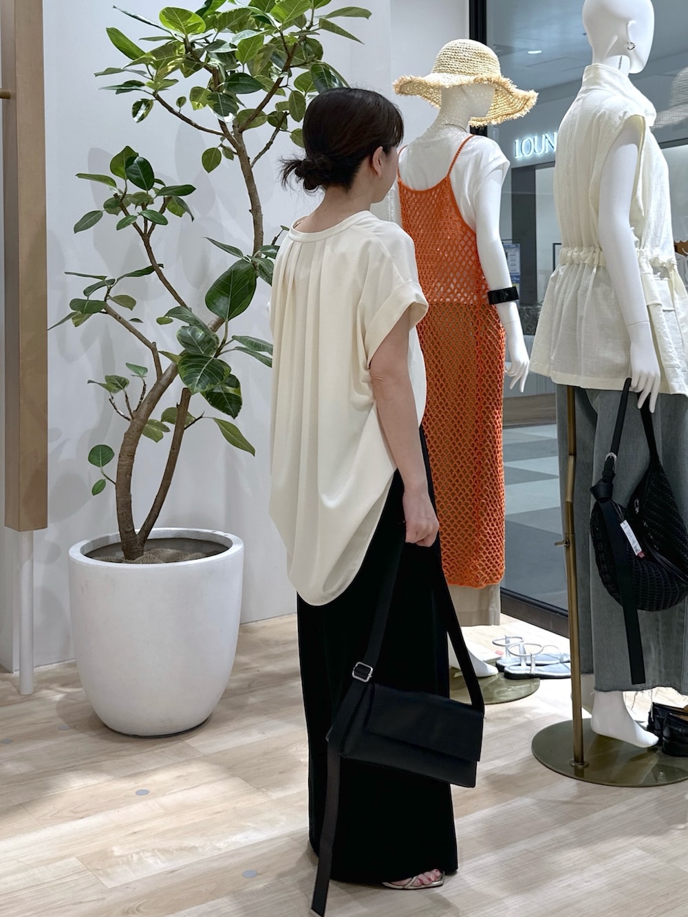 ブラック系のショルダーバッグ、ブラック系のスラックス、ホワイト系のタンクトップを着用したレディースの夏コーディネートの5枚目の写真