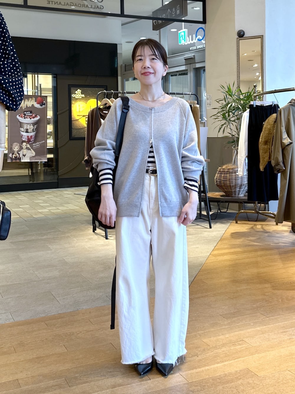 ブラック系のパンプス、ホワイト系のデニムパンツ、グレー系のニット/セーターを着用したレディースの秋コーディネートの3枚目の写真