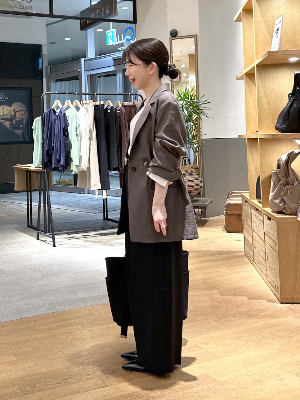 ブラック系のスラックス、ブラック系のパンプス、ブラック系のトートバッグを着用したレディースの秋コーディネートの3枚目の写真
