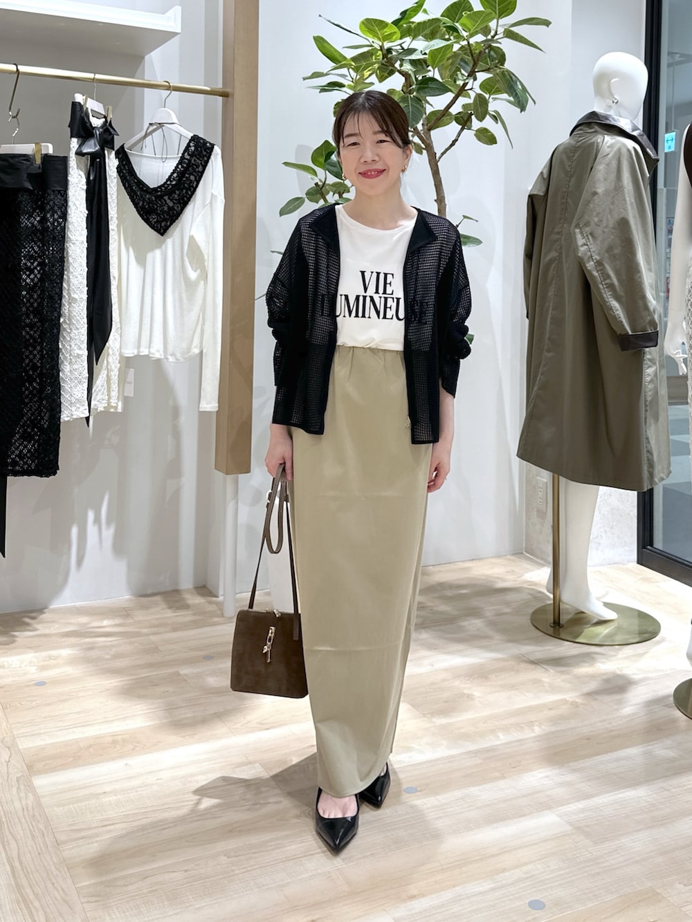 ベージュ系のスカート、ブラック系のパンプス、ブラウン系のショルダーバッグを着用したレディースの夏コーディネートの2枚目の写真