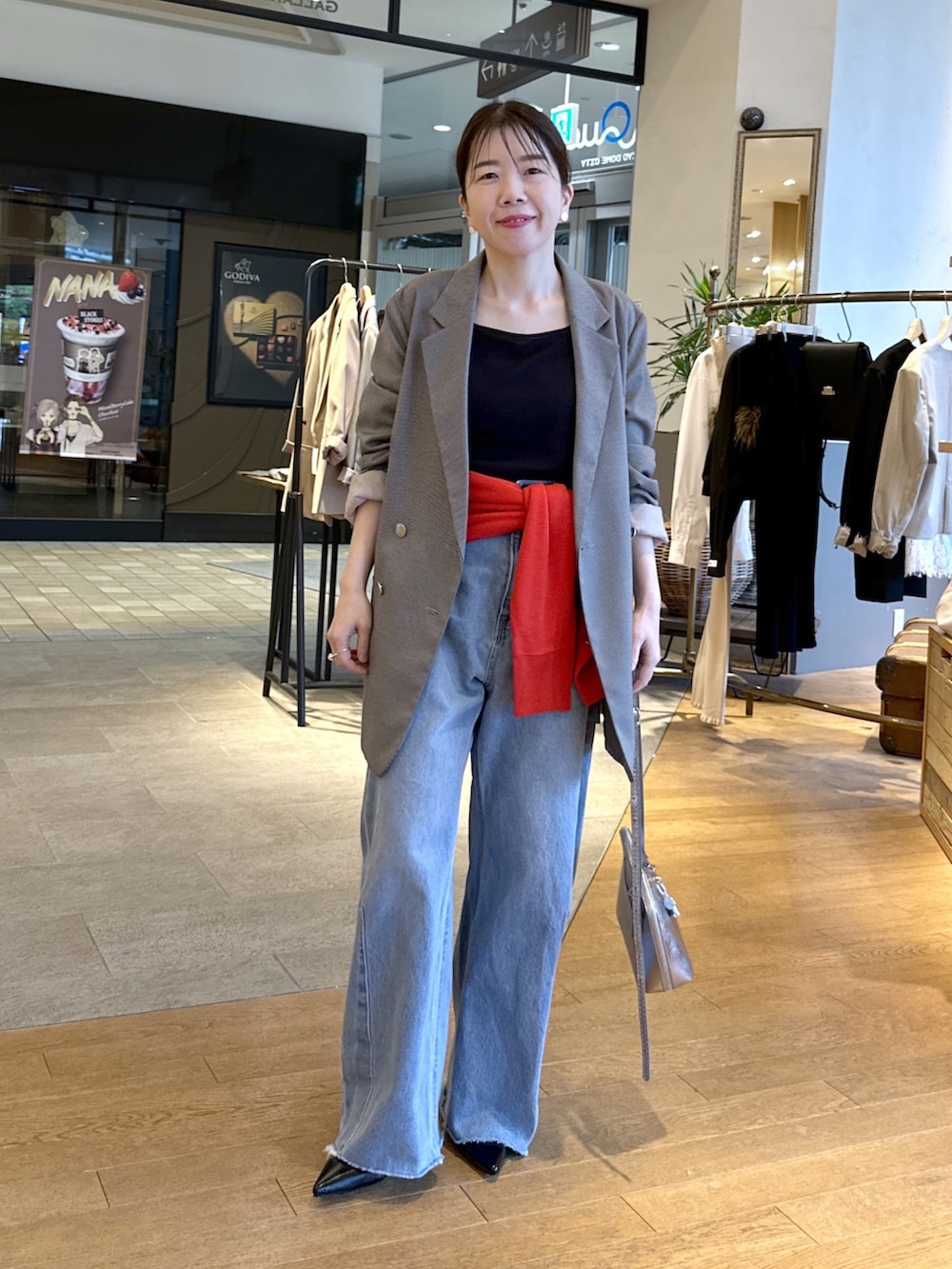 ブルー系のデニムパンツ、ブラック系のパンプス、レッド系のニット/セーターを着用したレディースの秋コーディネートの2枚目の写真