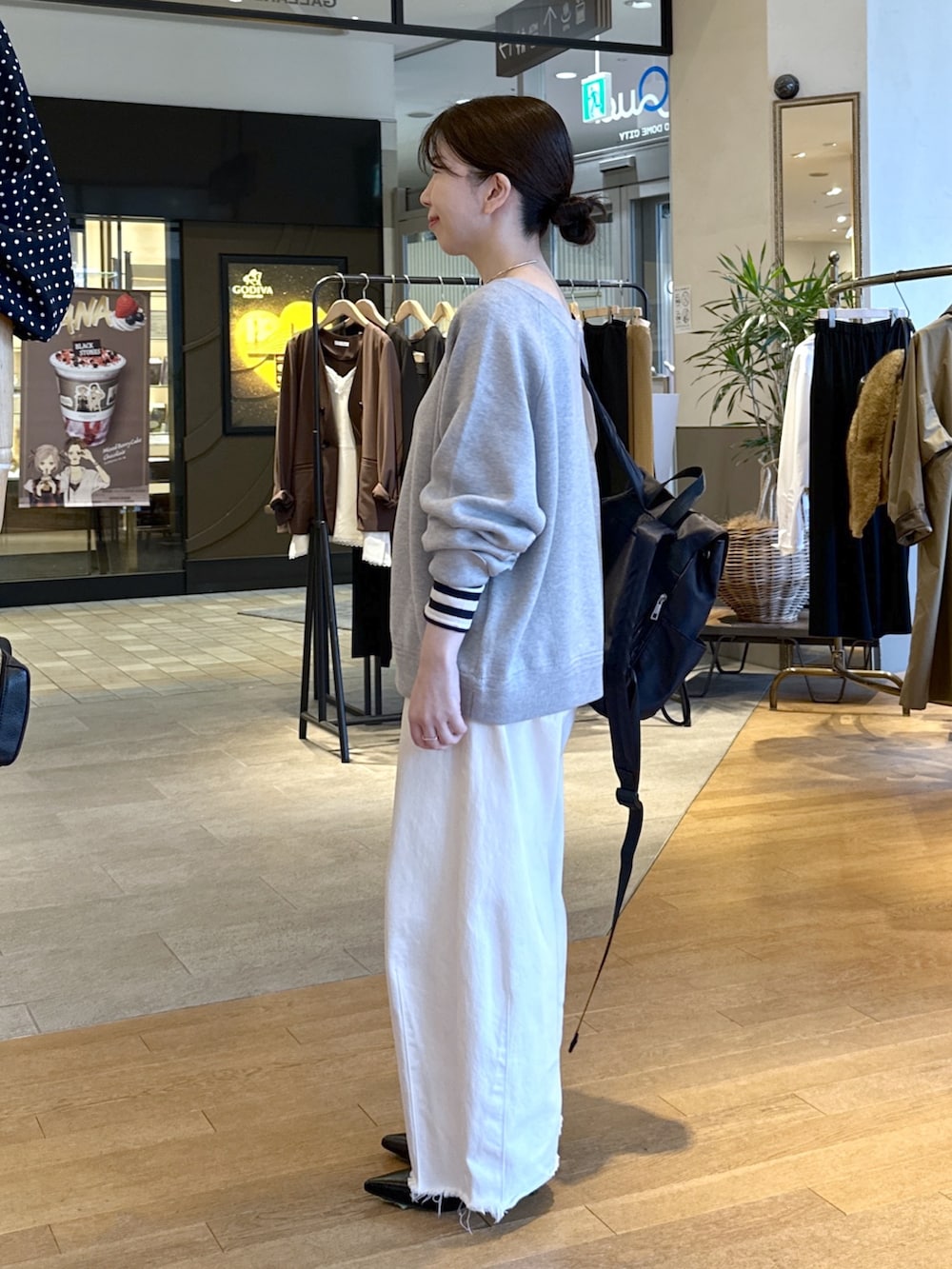 ブラック系のパンプス、ホワイト系のデニムパンツ、グレー系のニット/セーターを着用したレディースの秋コーディネートの4枚目の写真