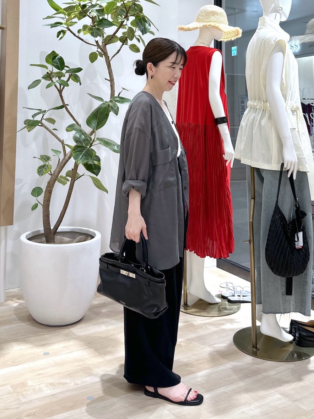ブラック系のサンダル、ブラック系のスラックス、ブラック系のトートバッグを着用したレディースの夏コーディネートの3枚目の写真