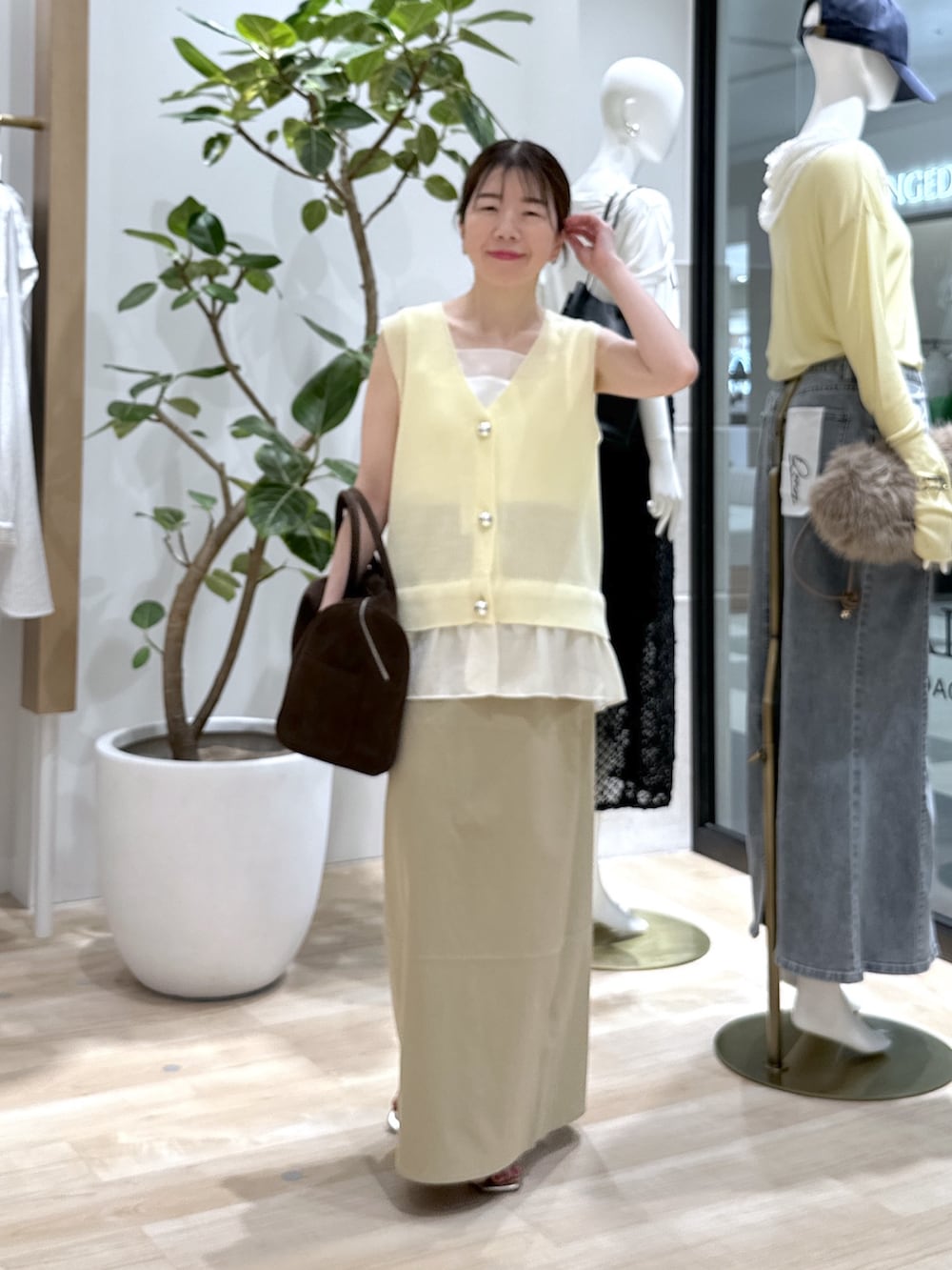 ベージュ系のスカート、ブラウン系のボストンバッグ、イエロー系のベストを着用したレディースの夏コーディネートの2枚目の写真