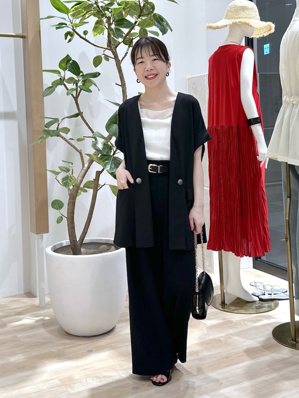 ブラック系のサンダル、ブラック系のショルダーバッグ、ブラック系のスラックスを着用したレディースの夏コーディネートの2枚目の写真