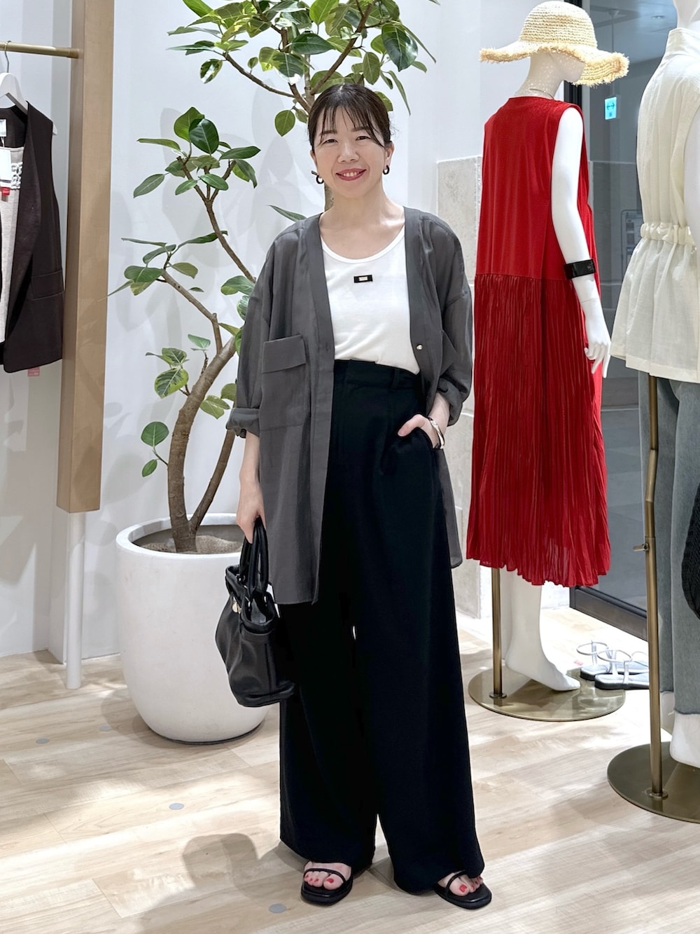 ブラック系のサンダル、ブラック系のスラックス、ブラック系のトートバッグを着用したレディースの夏コーディネートの2枚目の写真