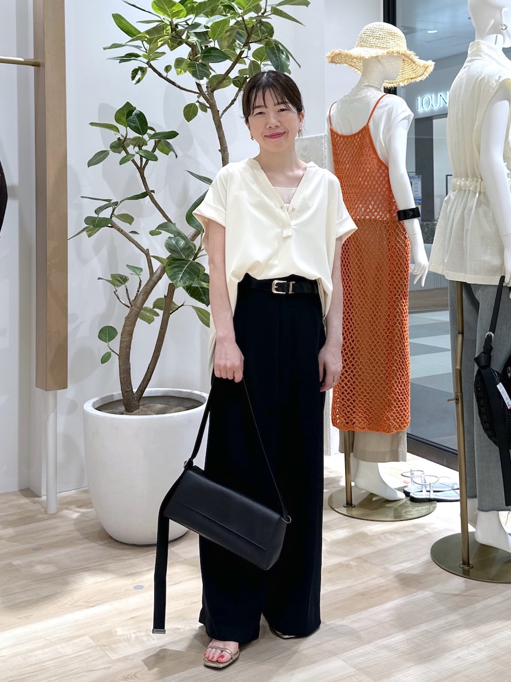 ブラック系のショルダーバッグ、ブラック系のスラックス、ホワイト系のタンクトップを着用したレディースの夏コーディネートの2枚目の写真