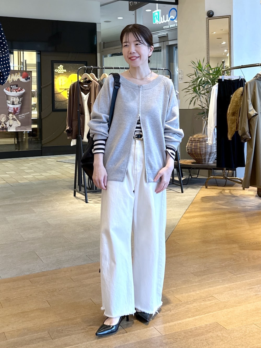 ブラック系のパンプス、ホワイト系のデニムパンツ、グレー系のニット/セーターを着用したレディースの秋コーディネートの2枚目の写真