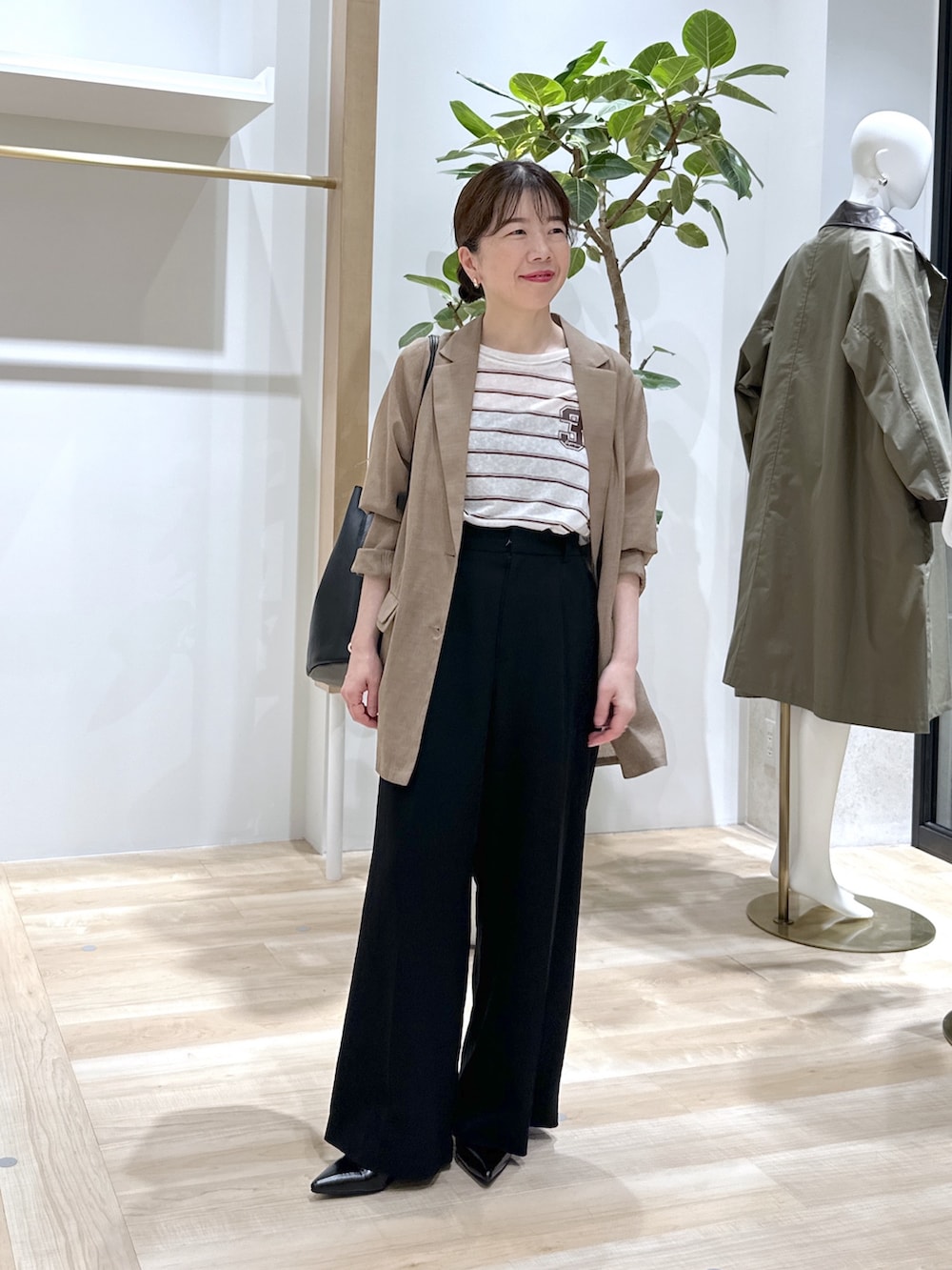 ブラック系のパンプス、ブラック系のスラックス、ベージュ系のテーラードジャケットを着用したレディースの夏コーディネートの2枚目の写真