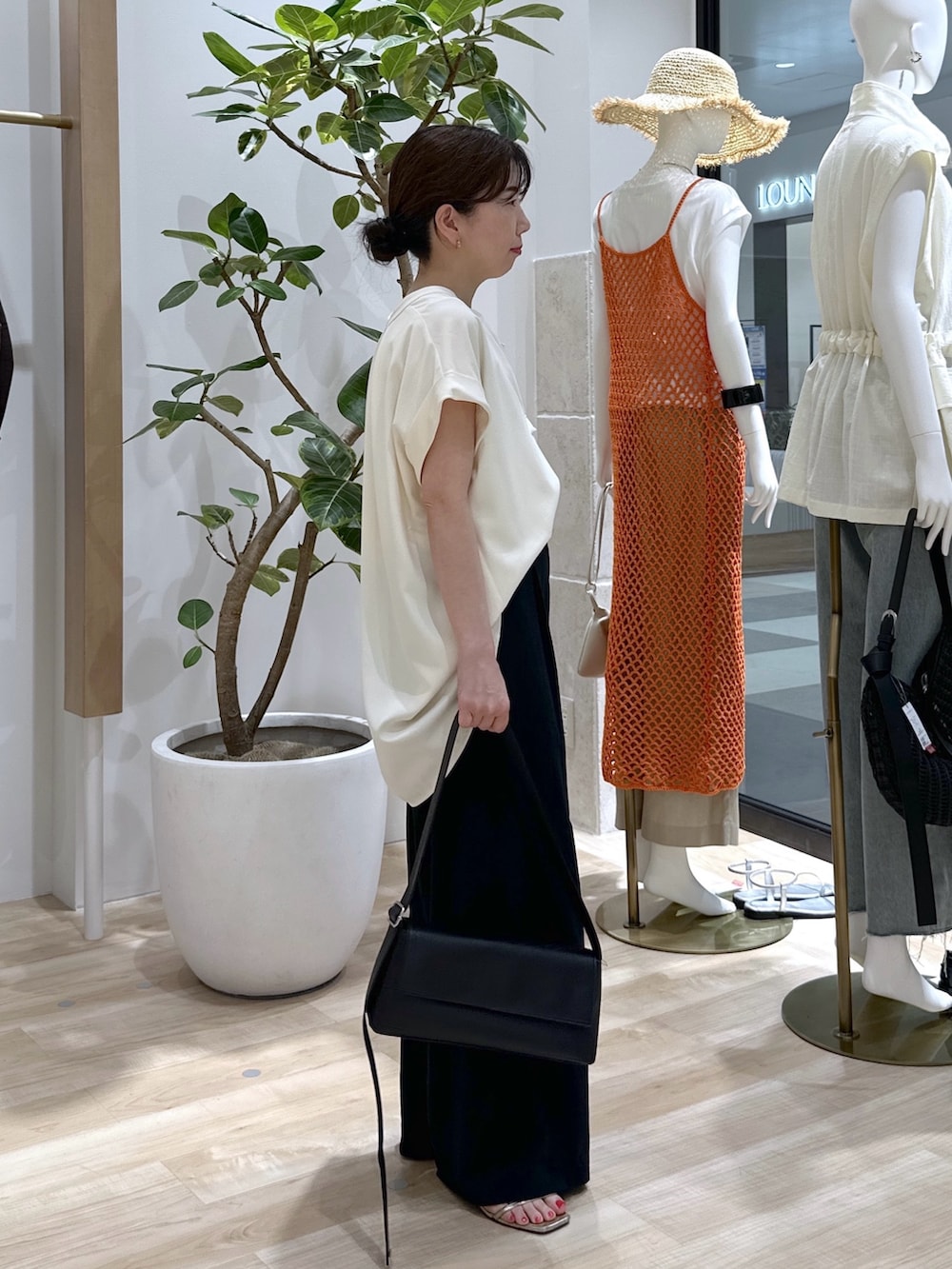 ブラック系のショルダーバッグ、ブラック系のスラックス、ホワイト系のタンクトップを着用したレディースの夏コーディネートの4枚目の写真