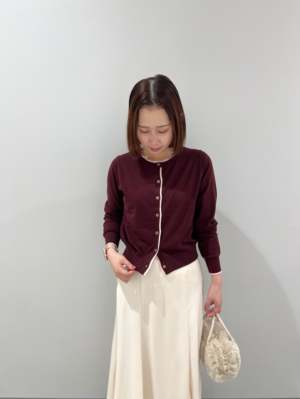 レッド系のカーディガン/ボレロ、ホワイト系のスカート、ホワイト系のボストンバッグを着用したレディースの秋コーディネートの4枚目の写真