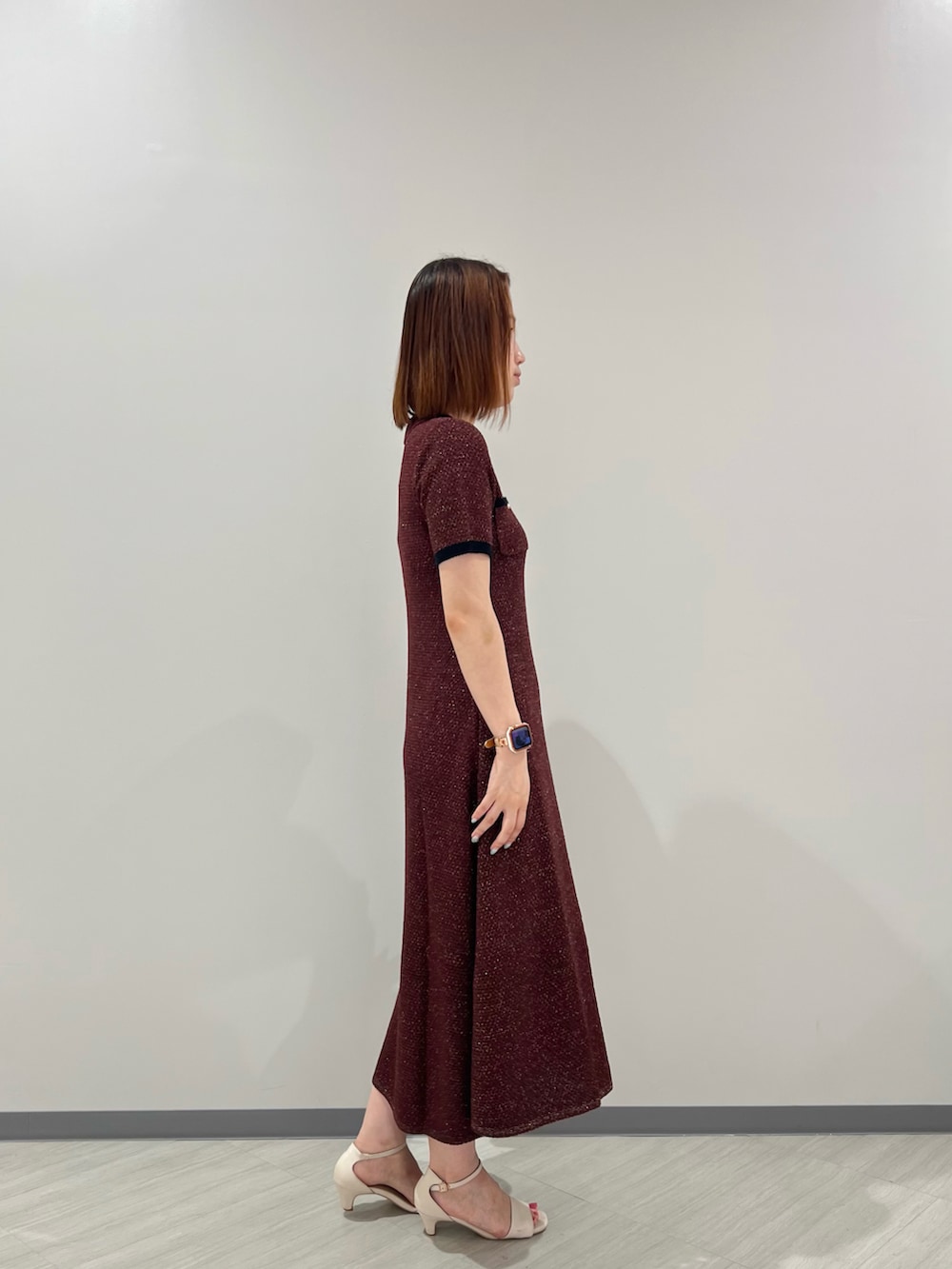 レッド系のワンピース、ブラウン系のボストンバッグ、ホワイト系のサンダルを着用したレディースの夏コーディネートの2枚目の写真