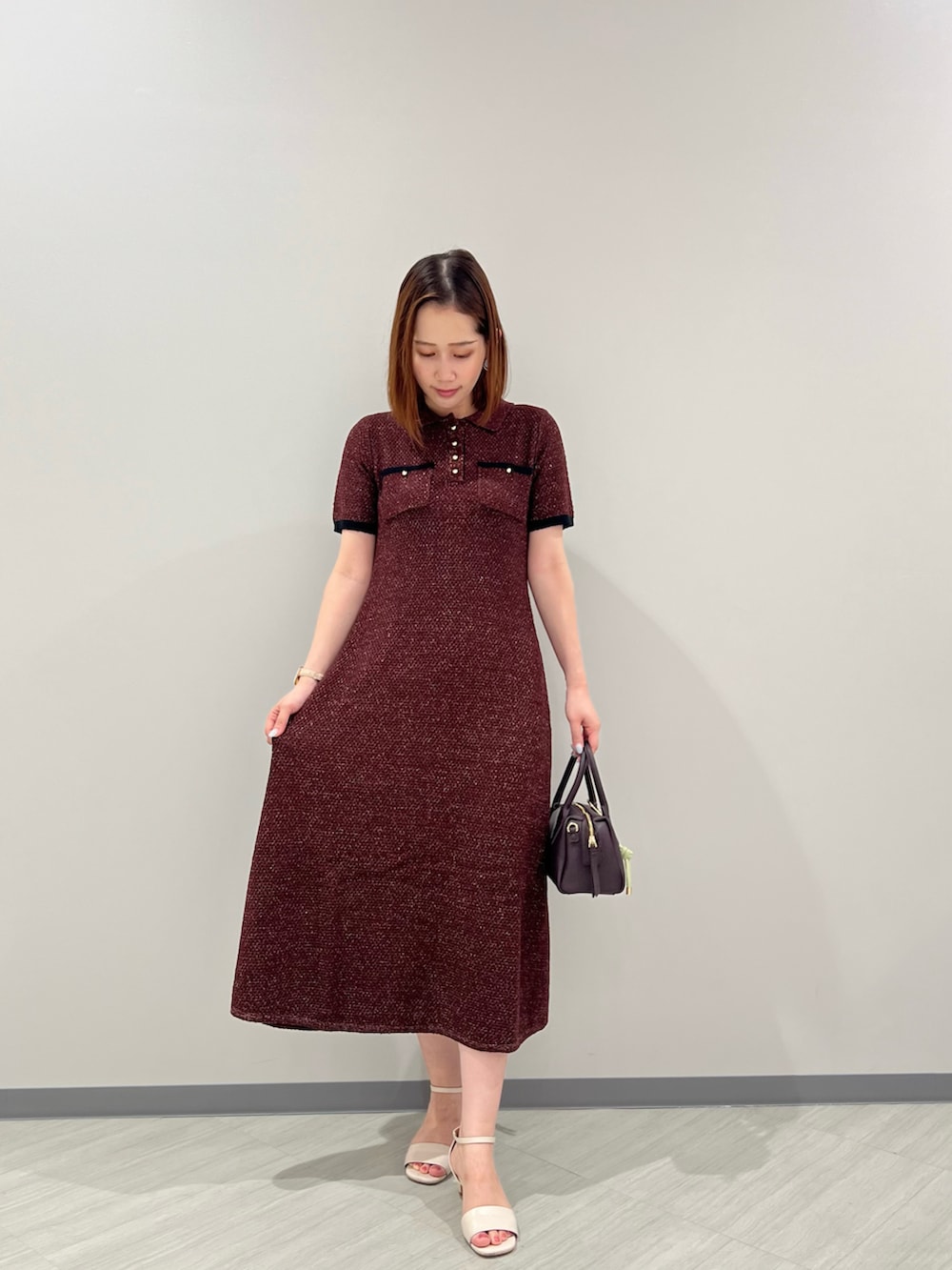 レッド系のワンピース、ブラウン系のボストンバッグ、ホワイト系のサンダルを着用したレディースの夏コーディネートの4枚目の写真
