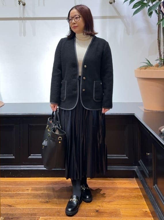 ブラック系のノーカラージャケット、ホワイト系のTシャツ/カットソー、ブルー系のスカートを着用したレディースの冬コーディネートの2枚目の写真
