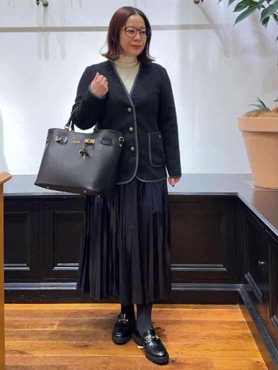 ブラック系のノーカラージャケット、ホワイト系のTシャツ/カットソー、ブルー系のスカートを着用したレディースの冬コーディネートの4枚目の写真