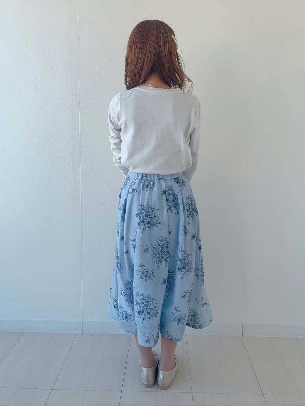 ゴールド系のパンプス、ブルー系のスカート、ホワイト系のニット/セーターを着用したレディースの春コーディネートの3枚目の写真