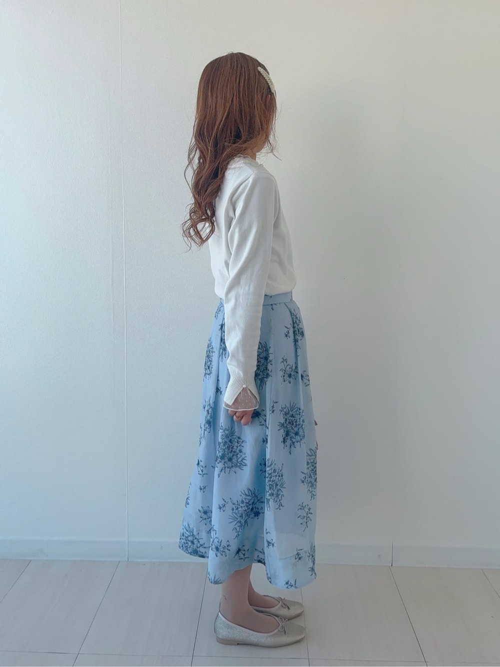 ゴールド系のパンプス、ブルー系のスカート、ホワイト系のニット/セーターを着用したレディースの春コーディネートの2枚目の写真