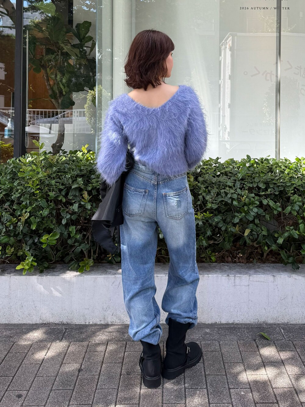 ブルー系のニット/セーター、ブラック系のブルゾン、ブルー系のデニムパンツを着用したレディースの秋コーディネートの3枚目の写真