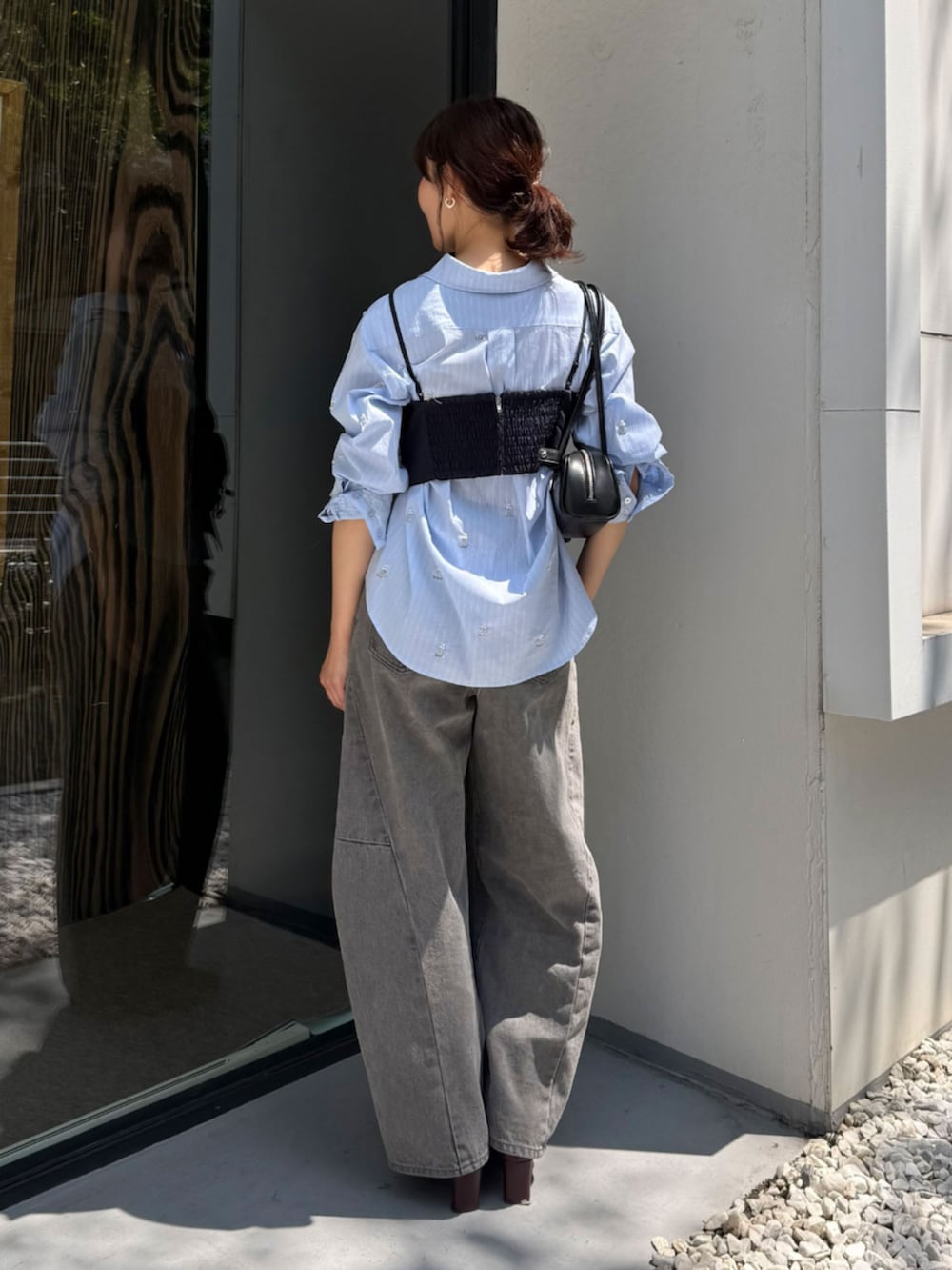 レッド系のブーツ、グレー系のデニムパンツ、ブルー系のシャツ/ブラウスを着用したレディースの秋コーディネートの3枚目の写真