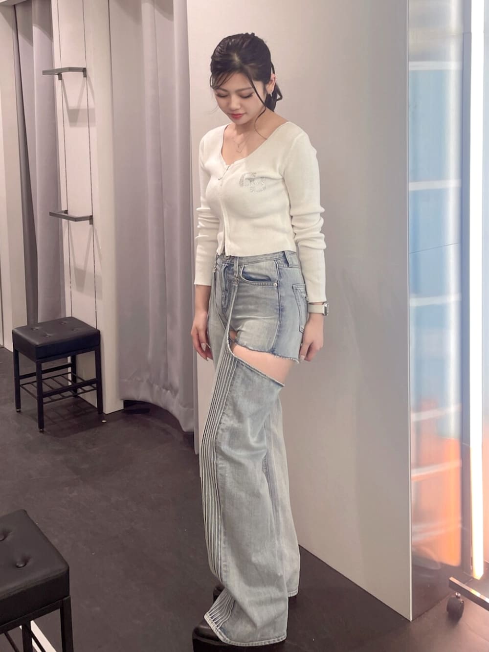 ブラック系のブーツ、ホワイト系のニット/セーター、ブルー系のデニムパンツを着用したレディースの春コーディネートの2枚目の写真