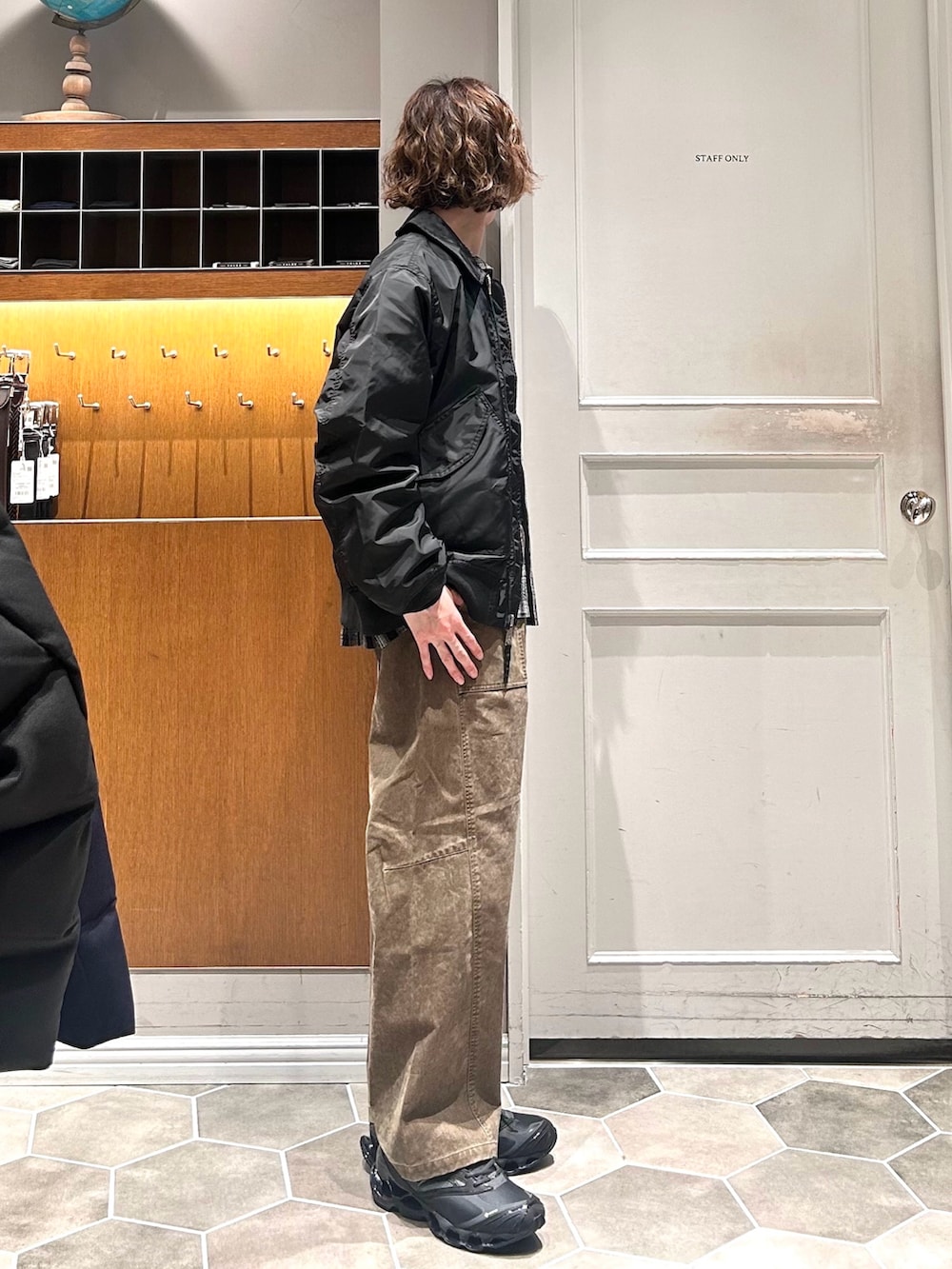 ブラック系のブルゾン、グリーン系のチノパンツ、ブラック系のスニーカーを着用したメンズの春コーディネートの3枚目の写真