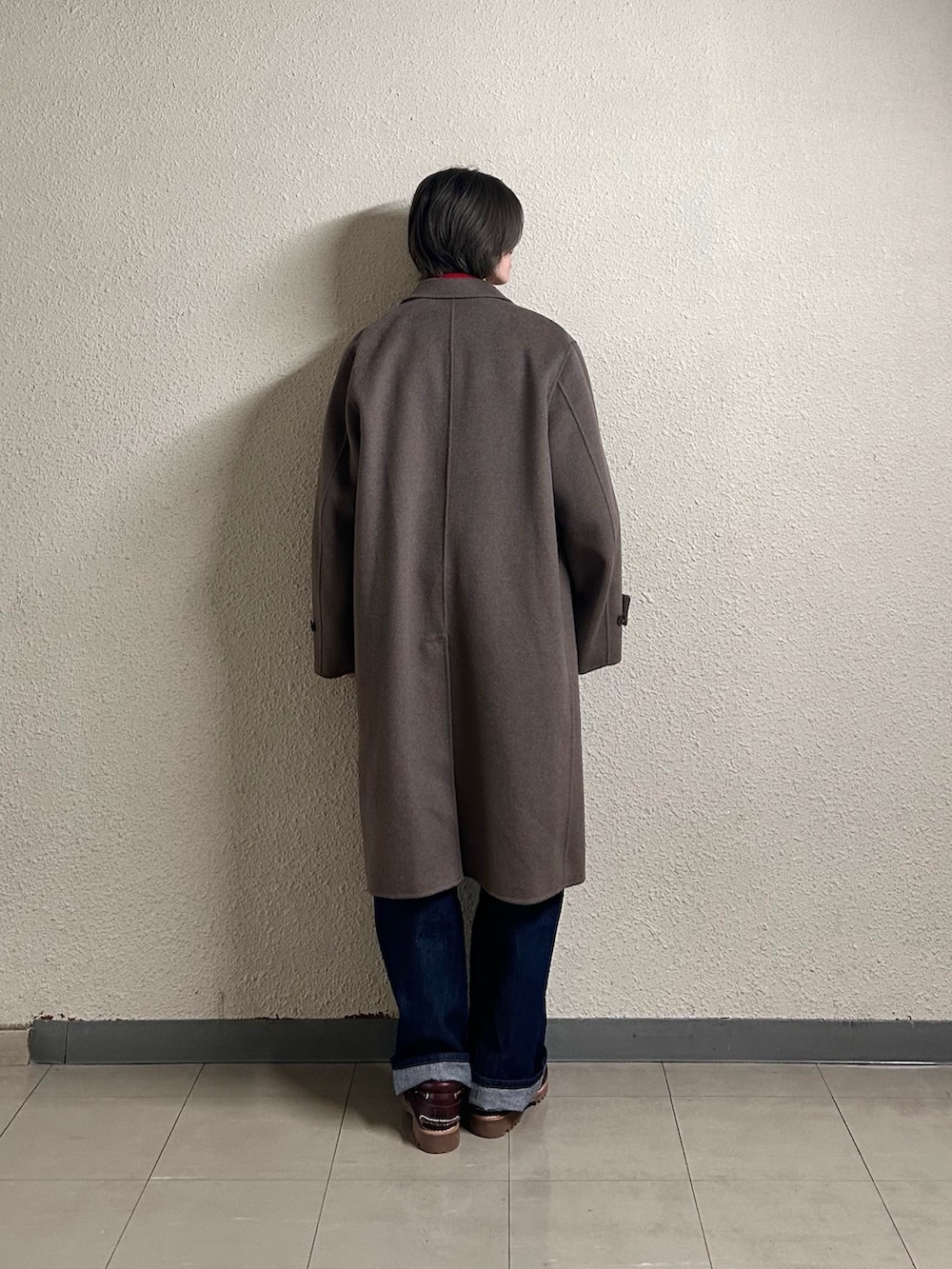 ブルー系のデニムパンツ、ホワイト系のニット/セーター、ブラウン系のチェスターコートを着用したメンズの春コーディネートの3枚目の写真