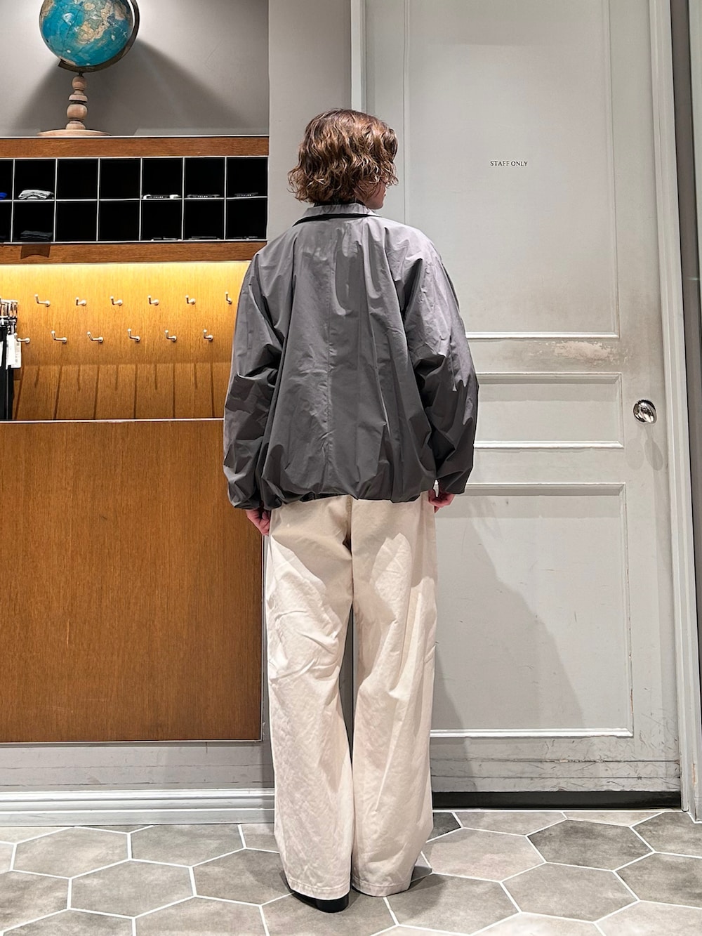 グレー系のナイロンジャケット、ホワイト系のチノパンツ、ブラック系のローファーを着用したメンズの春コーディネートの3枚目の写真