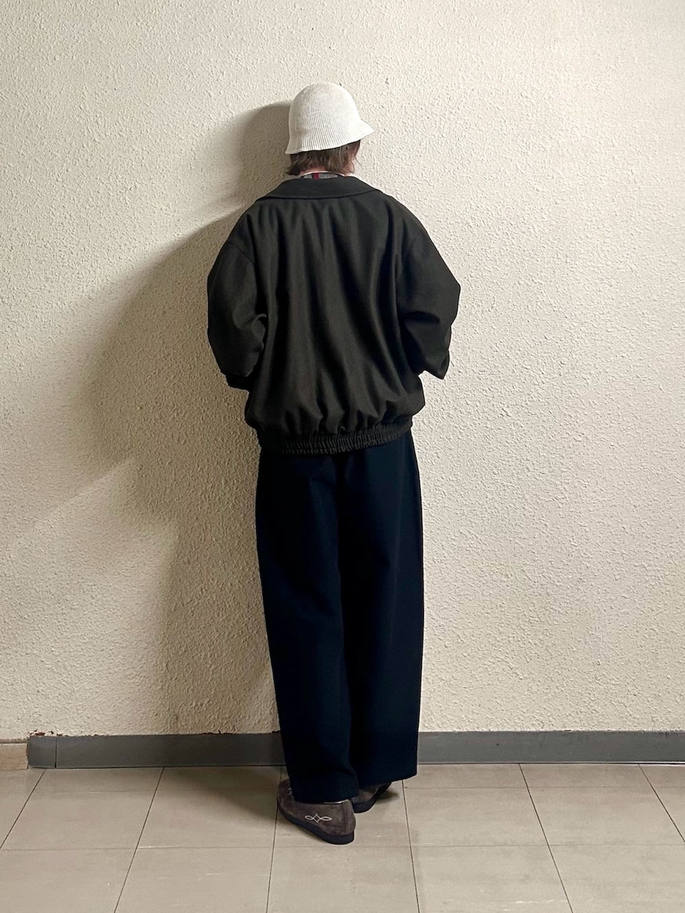 レッド系のベスト、ブラック系のパンツ、ブラウン系のシューズを着用したメンズの春コーディネートの3枚目の写真