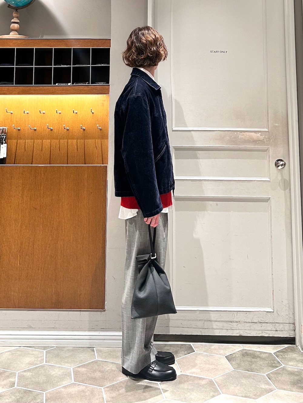 レッド系のニット/セーター、ブルー系のブルゾン、グレー系のスラックスを着用したメンズの春コーディネートの2枚目の写真