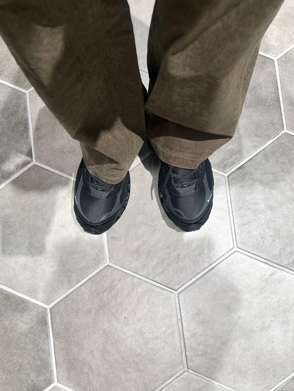 ブラック系のブルゾン、グリーン系のチノパンツ、ブラック系のスニーカーを着用したメンズの春コーディネートの5枚目の写真