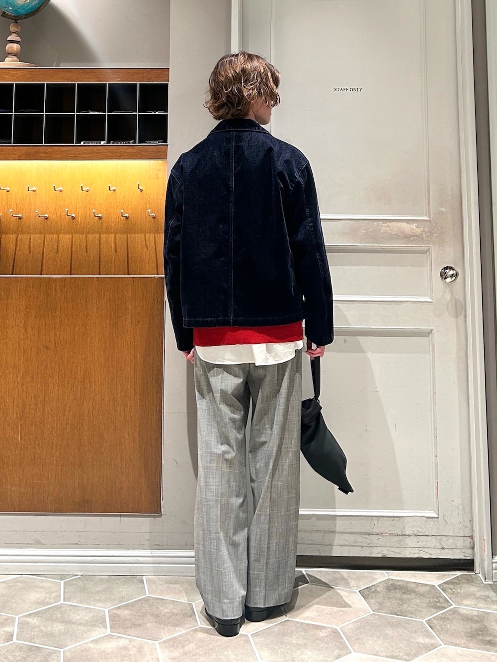 レッド系のニット/セーター、ブルー系のブルゾン、グレー系のスラックスを着用したメンズの春コーディネートの3枚目の写真
