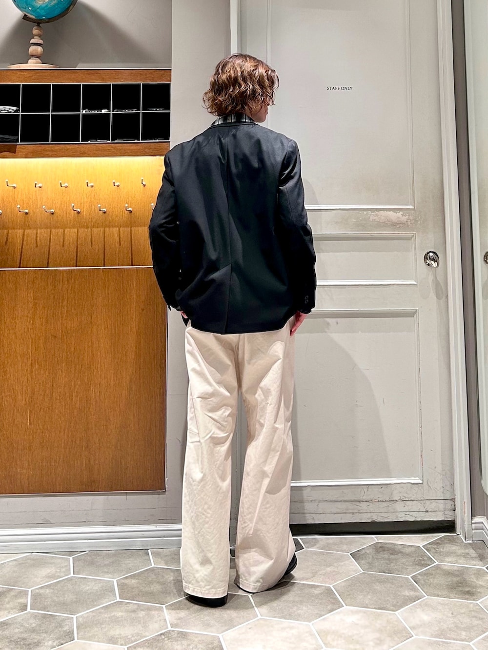 ブラック系のテーラードジャケット、ホワイト系のチノパンツを着用したメンズの春コーディネートの4枚目の写真