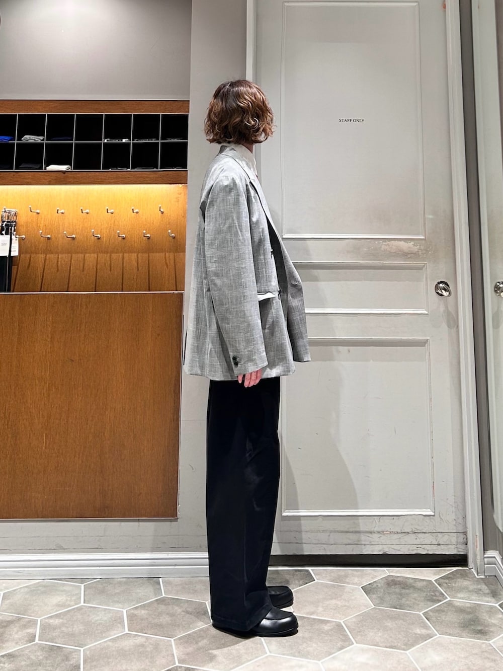 レッド系のニット/セーター、グレー系のテーラードジャケット、ブラック系のその他パンツを着用したメンズの春コーディネートの3枚目の写真